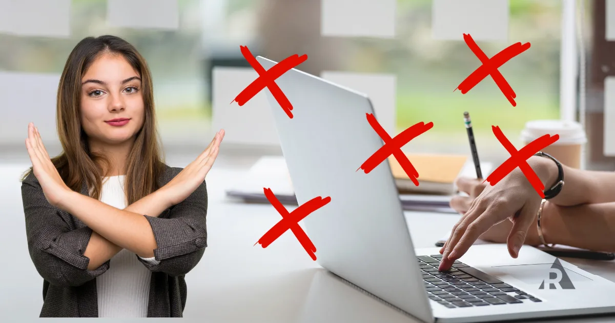 Woman gesturing ‘no’ with crossed arms beside a laptop